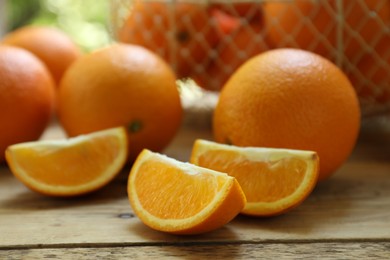 Photo of Fresh whole and cut oranges on wooden table, closeup