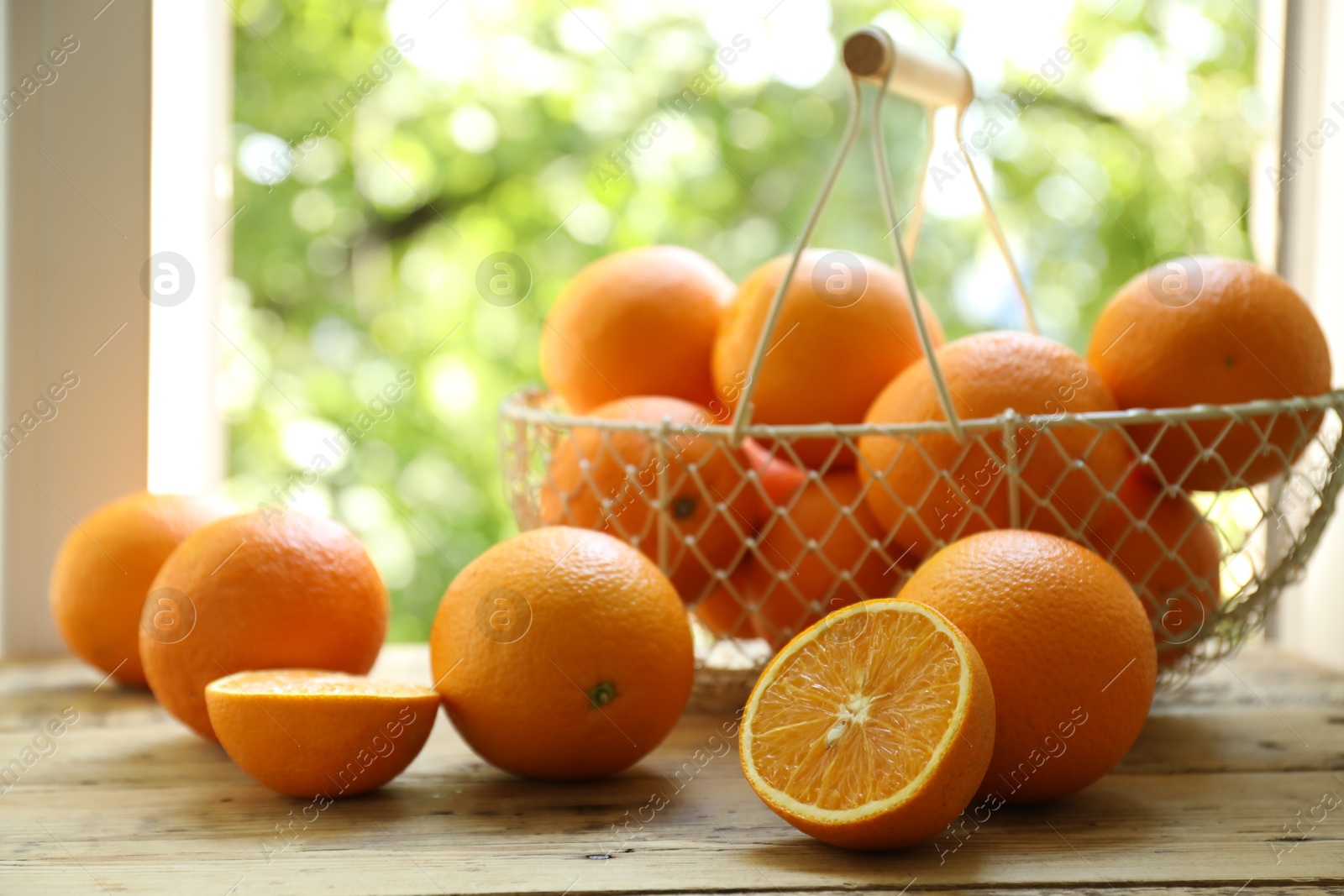 Fresh whole and cut oranges on wooden table against blurred green background, closeup Photo of Fresh whole and cut oranges on wooden table against blurred green background, closeup