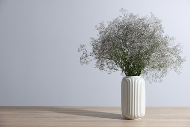Photo of Beautiful flowers in vase on wooden table against white background, space for text