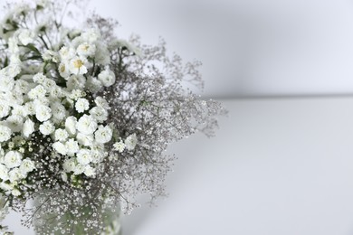 Photo of Beautiful flowers in vase on white table, closeup. Space for text