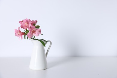 Photo of Beautiful flowers in vase on white table, space for text