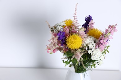Photo of Beautiful flowers in vase on white table, space for text