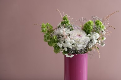 Photo of Beautiful flowers in vase on pink background, closeup. Space for text