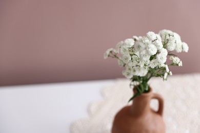 Photo of Beautiful flowers in vase on white table against pink background, closeup. Space for text