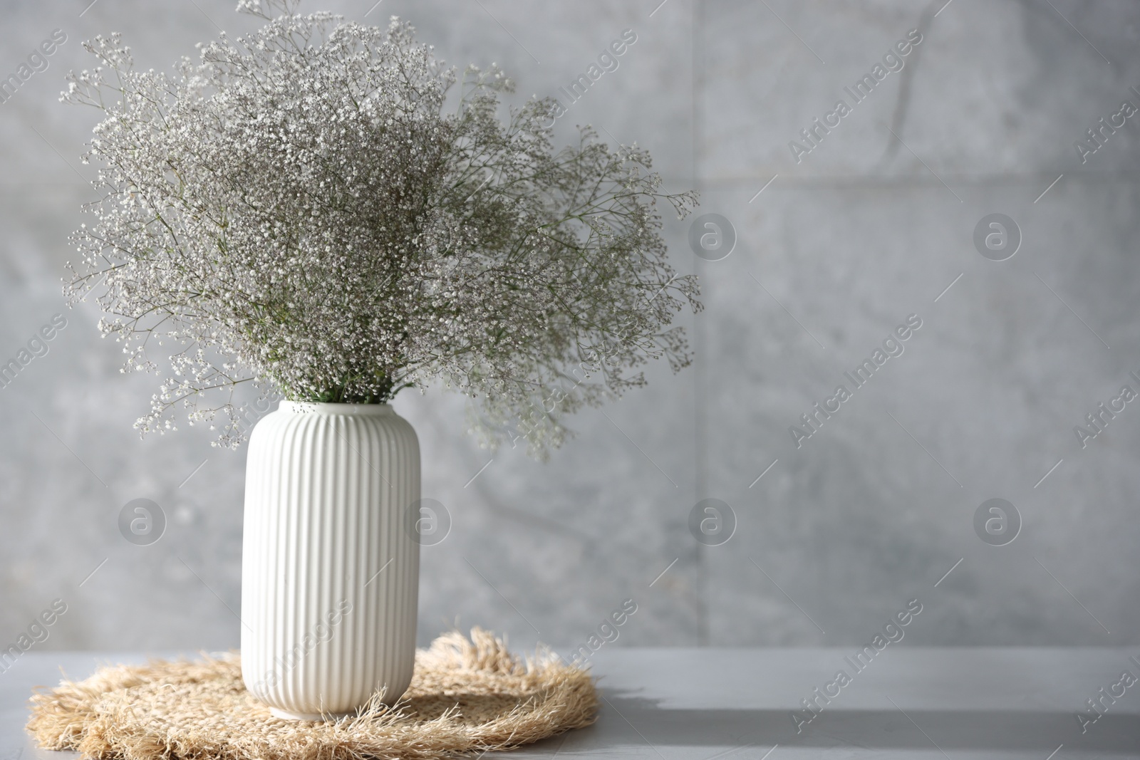 Beautiful flowers in vase on grey table, space for text Photo of Beautiful flowers in vase on grey table, space for text