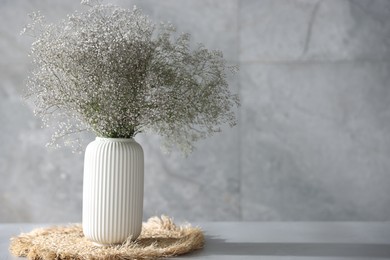 Photo of Beautiful flowers in vase on grey table, space for text
