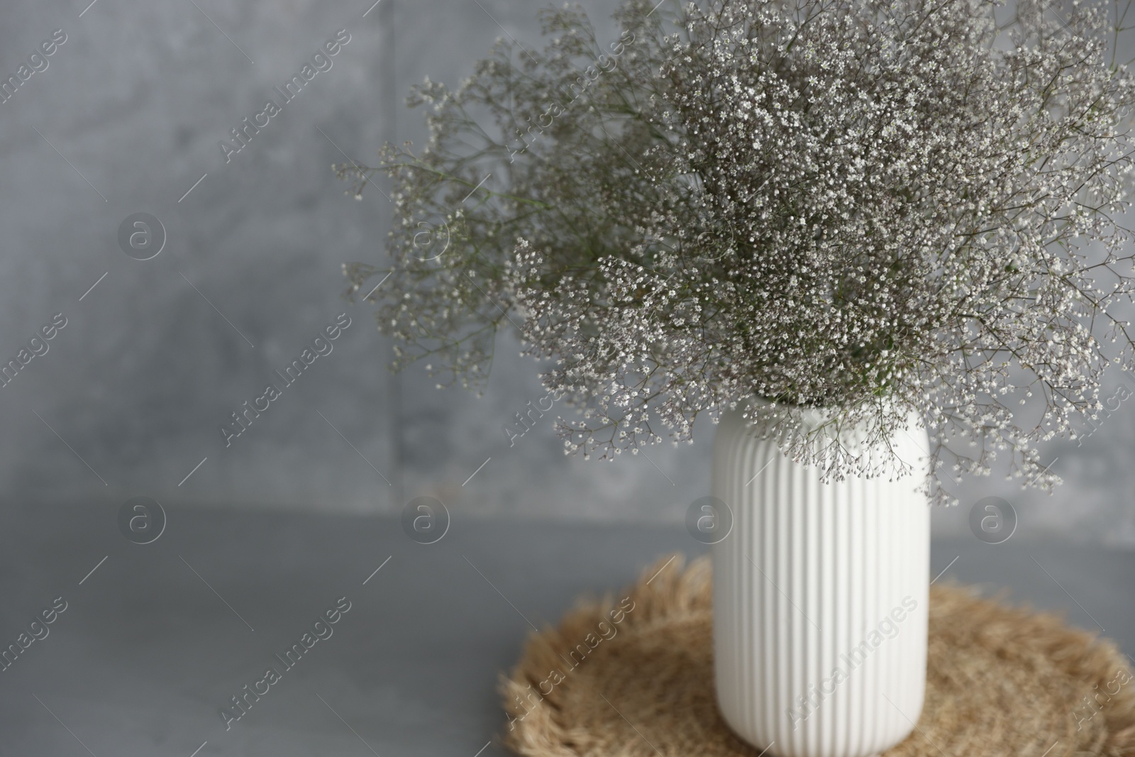 Photo of Beautiful flowers in vase on grey table, closeup. Space for text