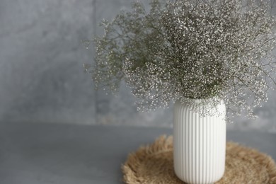 Photo of Beautiful flowers in vase on grey table, closeup. Space for text