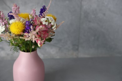Photo of Beautiful flowers in vase on grey table, closeup. Space for text