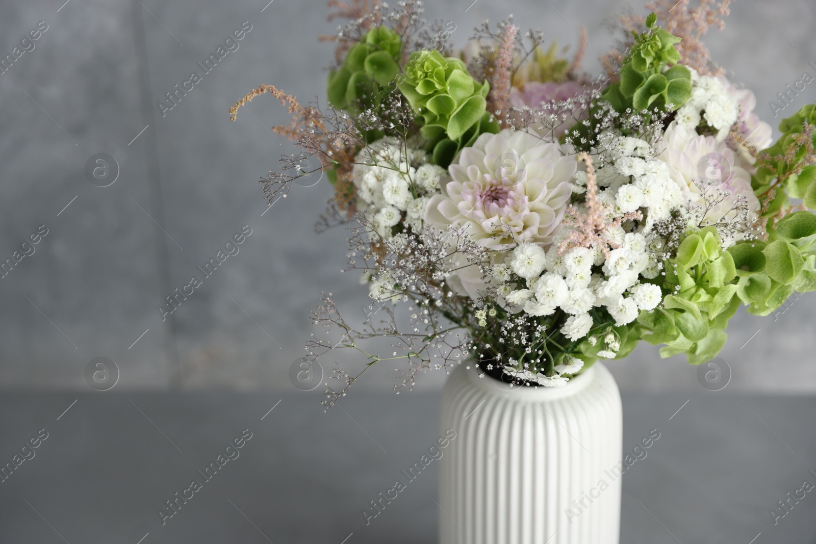 Beautiful flowers in vase on grey table, closeup. Space for text Photo of Beautiful flowers in vase on grey table, closeup. Space for text