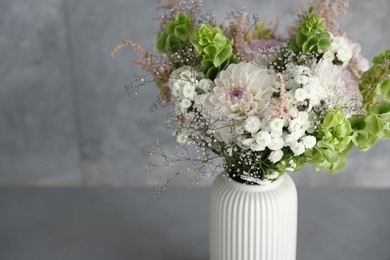 Photo of Beautiful flowers in vase on grey table, closeup. Space for text