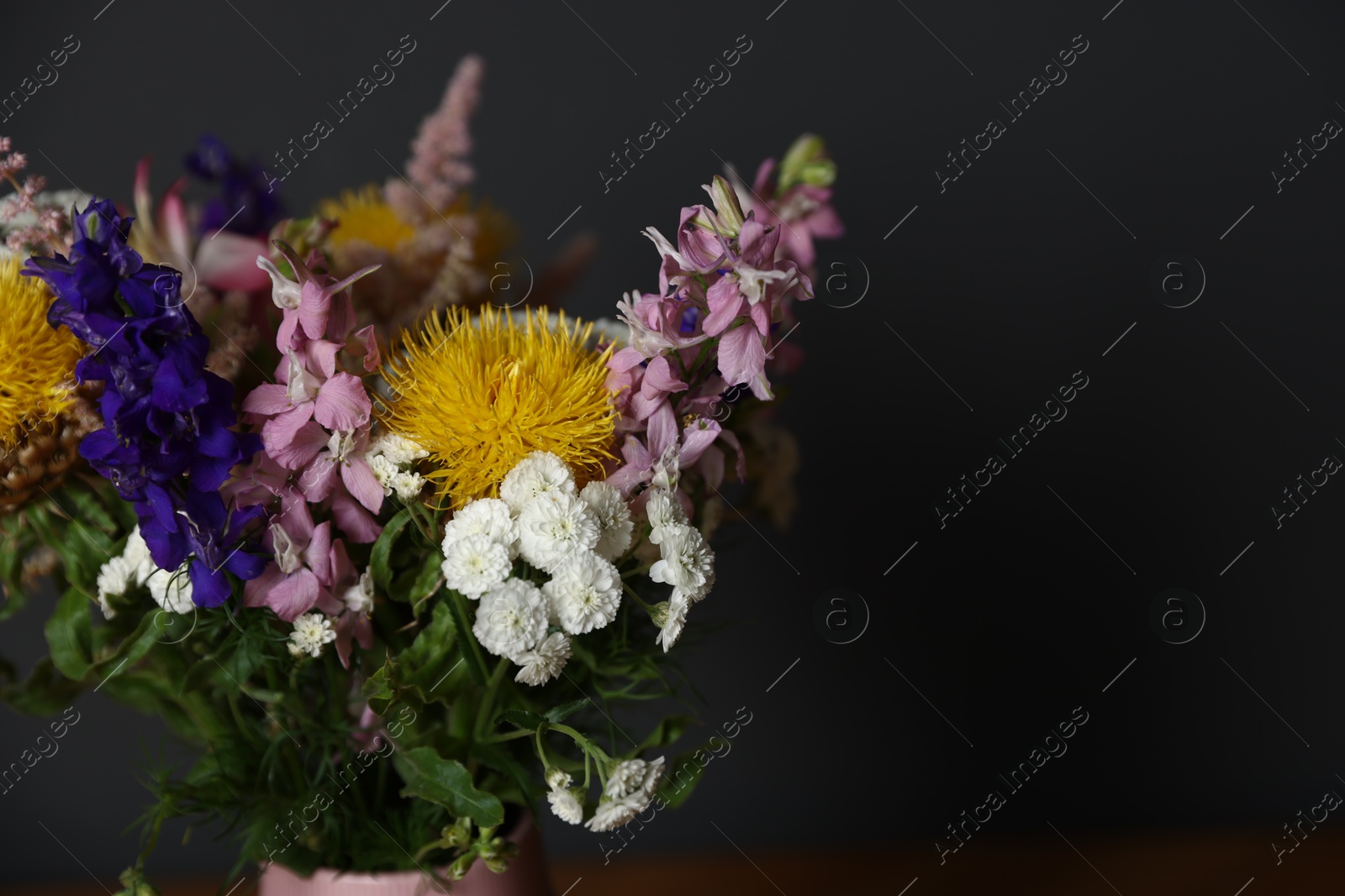 Beautiful flowers in vase on table against dark grey background, closeup. Space for text Photo of Beautiful flowers in vase on table against dark grey background, closeup. Space for text