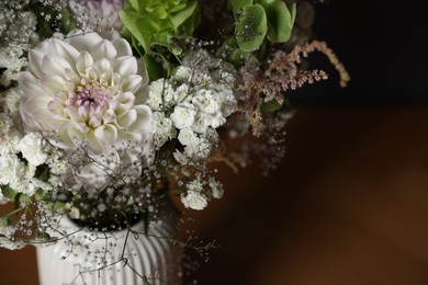 Photo of Beautiful flowers in vase on wooden table, closeup. Space for text