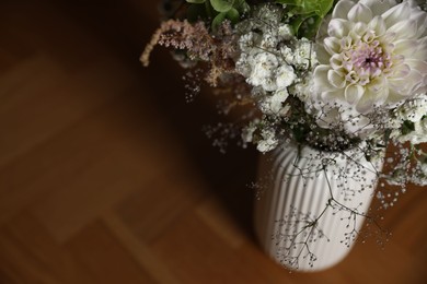 Photo of Beautiful flowers in vase on wooden table, closeup. Space for text