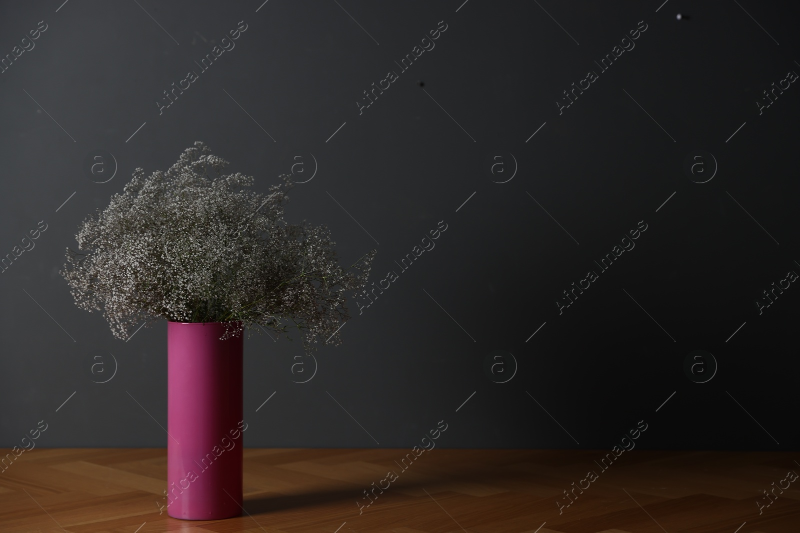 Beautiful flowers in vase on wooden table against dark grey background, space for text Photo of Beautiful flowers in vase on wooden table against dark grey background, space for text