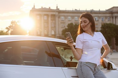 Photo of Beautiful woman with smartphone near modern car outdoors on sunny day