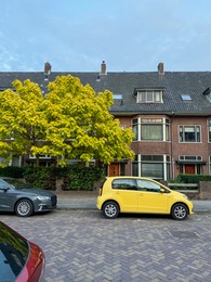 Photo of Parked cars, tree and building on city street