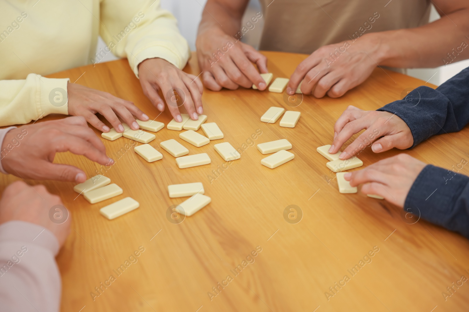 Friends playing dominoes at wooden table, closeup Photo of Friends playing dominoes at wooden table, closeup