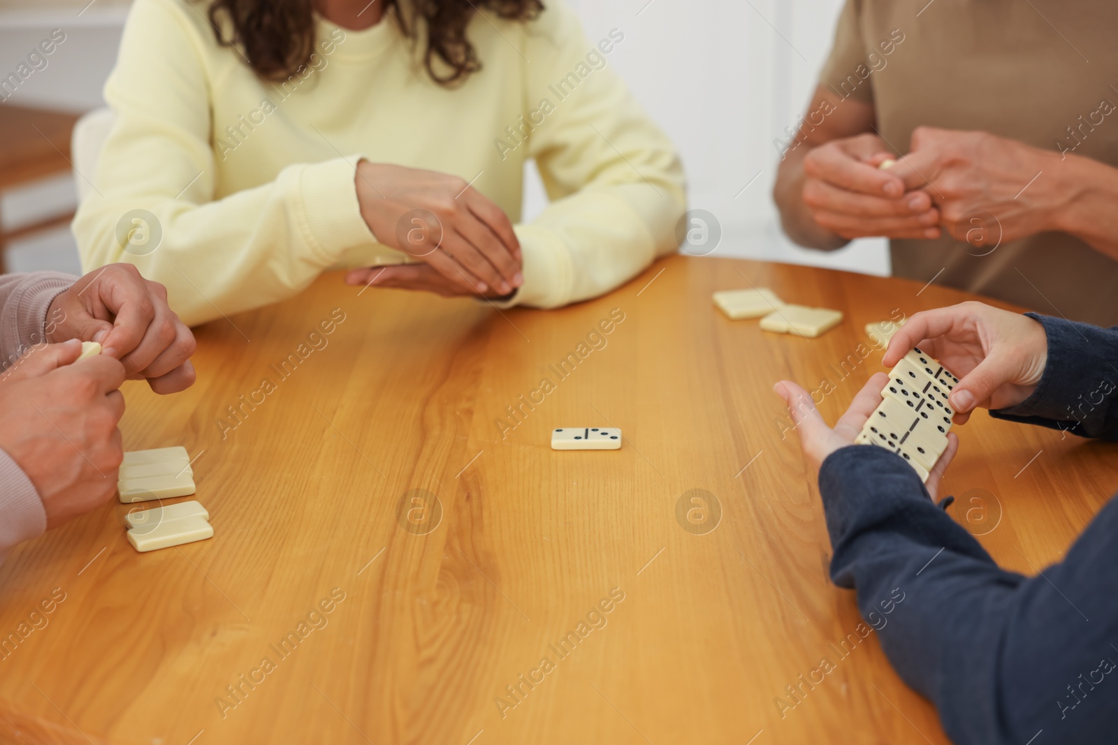 Friends playing dominoes at wooden table indoors, closeup Photo of Friends playing dominoes at wooden table indoors, closeup