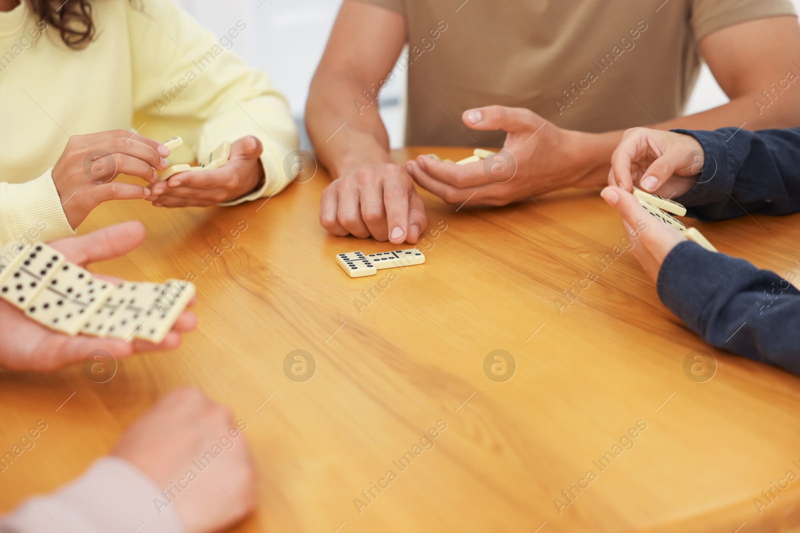 Friends playing dominoes at wooden table, closeup Photo of Friends playing dominoes at wooden table, closeup