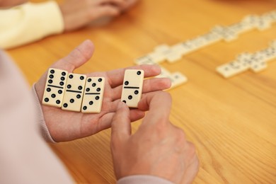 Photo of Friends playing dominoes at wooden table, closeup