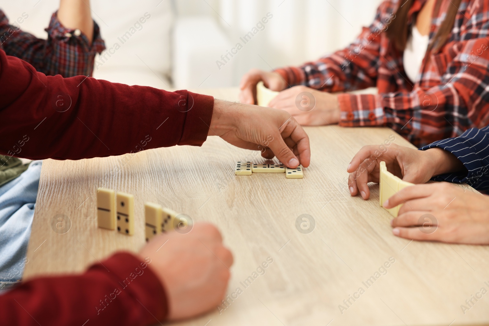 Friends playing dominoes at light wooden table, closeup Photo of Friends playing dominoes at light wooden table, closeup