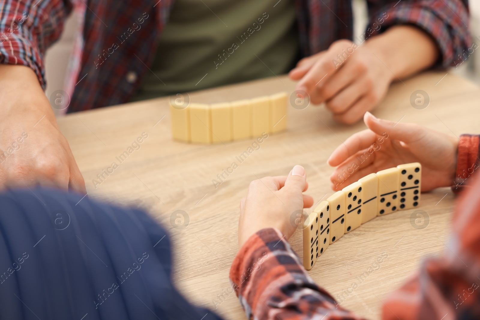 Friends playing dominoes at light wooden table, closeup Photo of Friends playing dominoes at light wooden table, closeup