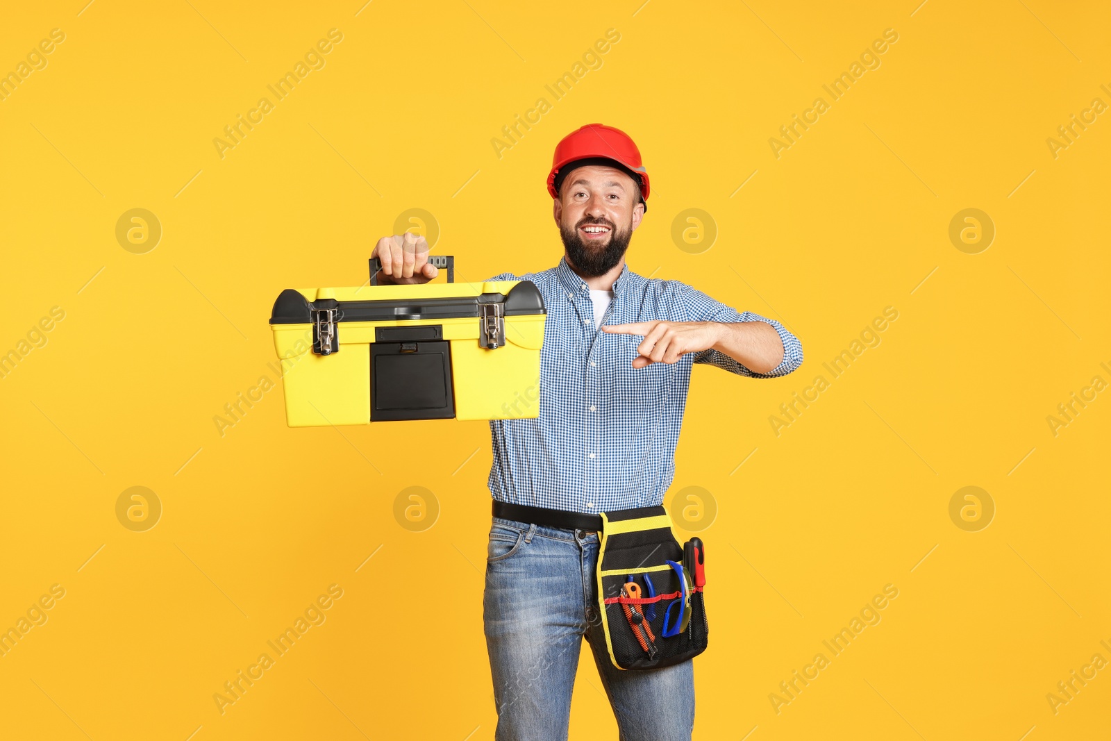 Professional repairman with tool box on orange background Photo of Professional repairman with tool box on orange background