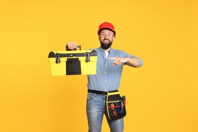 Photo of Professional repairman with tool box on orange background