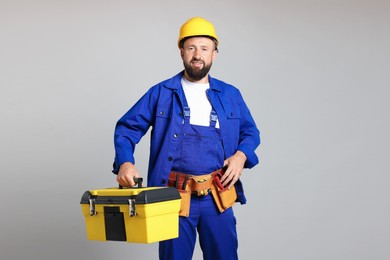 Photo of Professional repairman with tool box on grey background