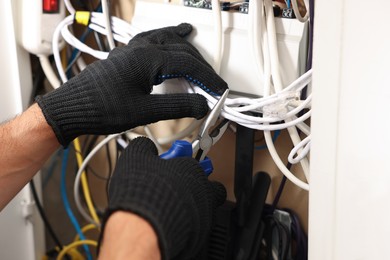 Photo of Man fixing heating radiator with pliers indoors, closeup