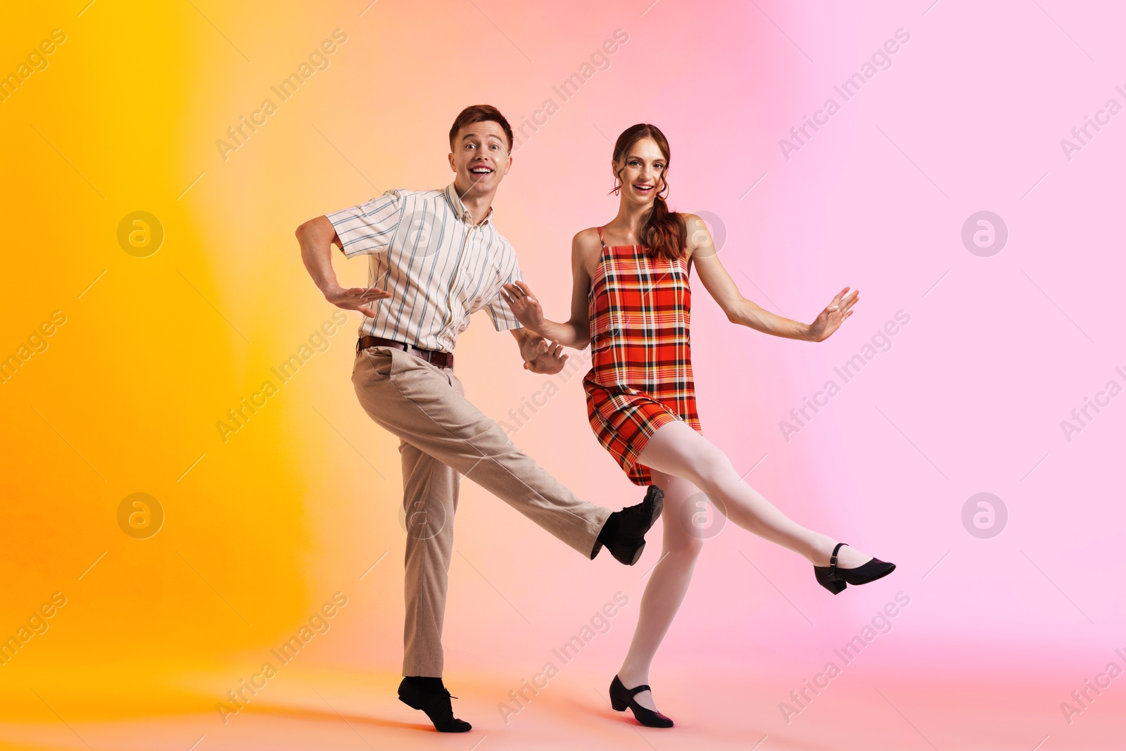 Happy couple in retro outfits dancing on color background Photo of Happy couple in retro outfits dancing on color background
