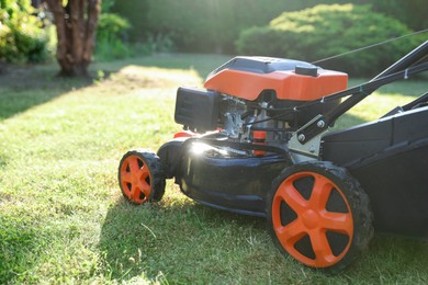 Photo of One lawn mower on green grass in garden, closeup. Space for text