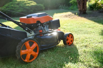 Photo of One lawn mower on green grass in garden, closeup. Space for text