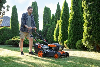 Photo of Man cutting green grass with lawn mower in garden