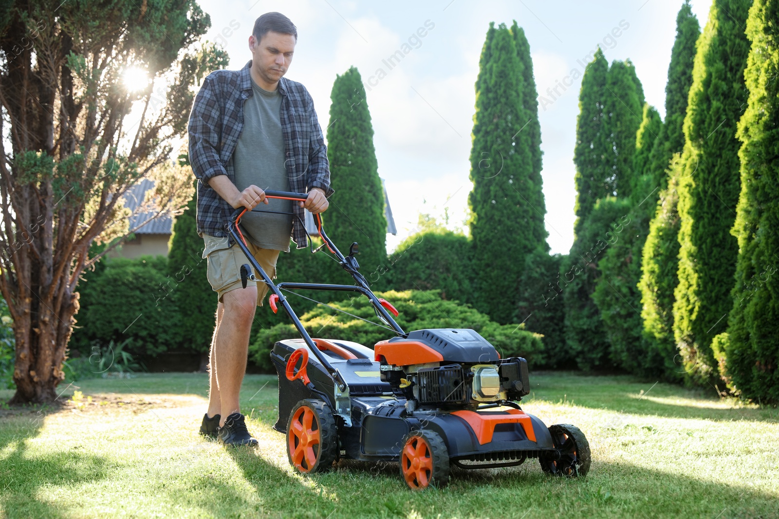 Man cutting green grass with lawn mower in garden Photo of Man cutting green grass with lawn mower in garden