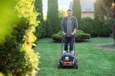 Photo of Man cutting green grass with lawn mower in garden