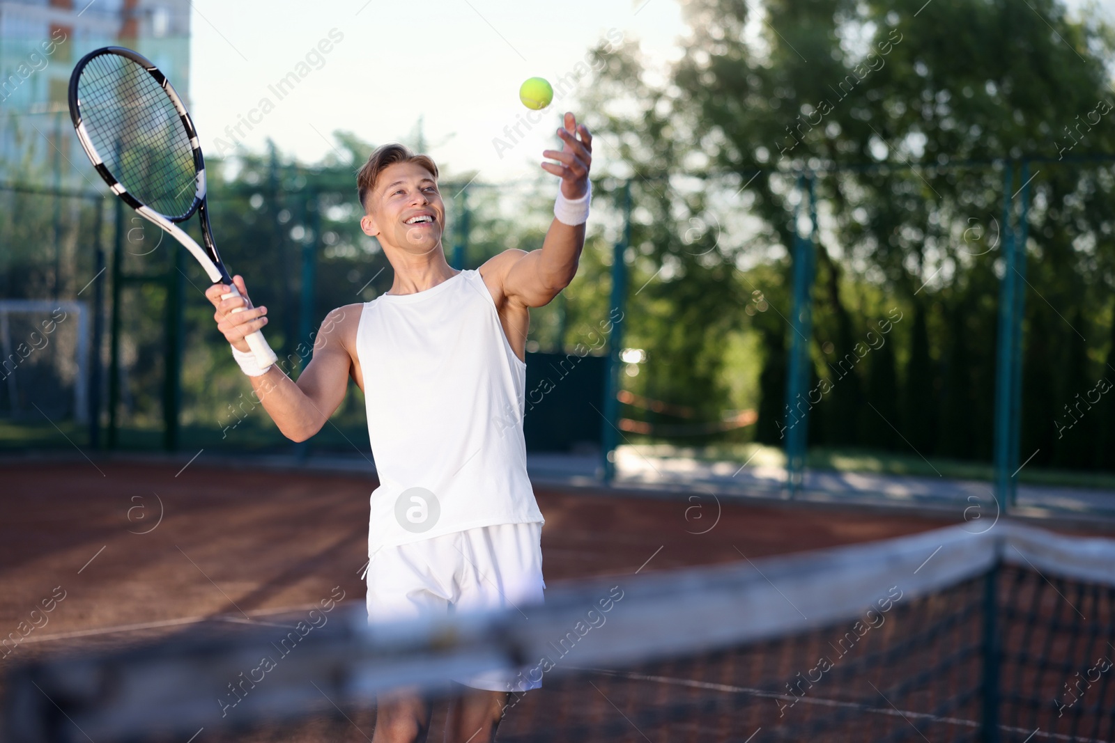 Young man playing tennis at court on sunny day. Space for text Photo of Young man playing tennis at court on sunny day. Space for text