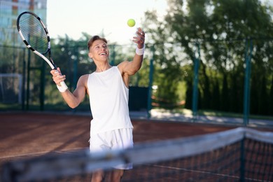 Photo of Young man playing tennis at court on sunny day. Space for text