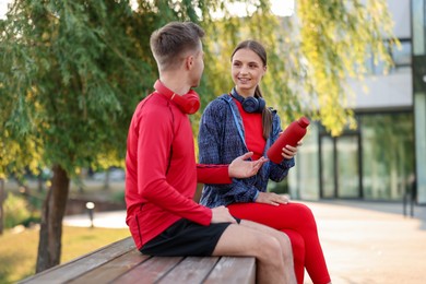 Photo of Happy couple resting on bench after morning exercises outdoors
