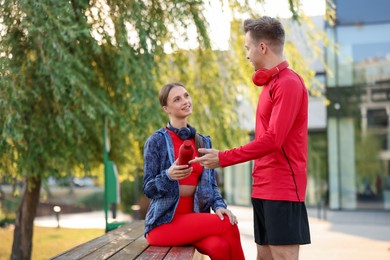 Photo of Happy couple resting on bench after morning exercises outdoors