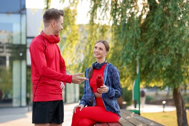 Photo of Happy couple resting on bench after morning exercises outdoors