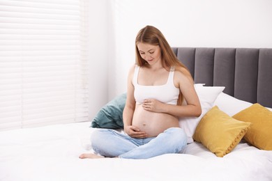 Photo of Beautiful pregnant woman on bed at home. Space for text