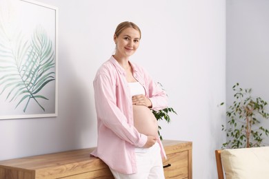 Photo of Beautiful pregnant woman touching her belly at home
