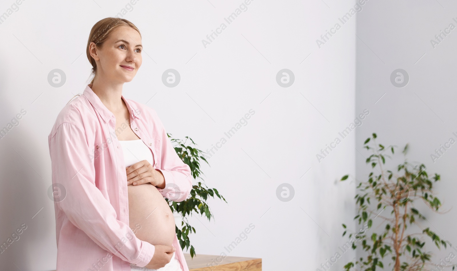 Beautiful pregnant woman touching her belly at home. Space for text Photo of Beautiful pregnant woman touching her belly at home. Space for text