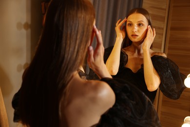 Photo of Beautiful woman getting ready near mirror indoors