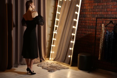 Photo of Beautiful woman getting ready near mirror indoors