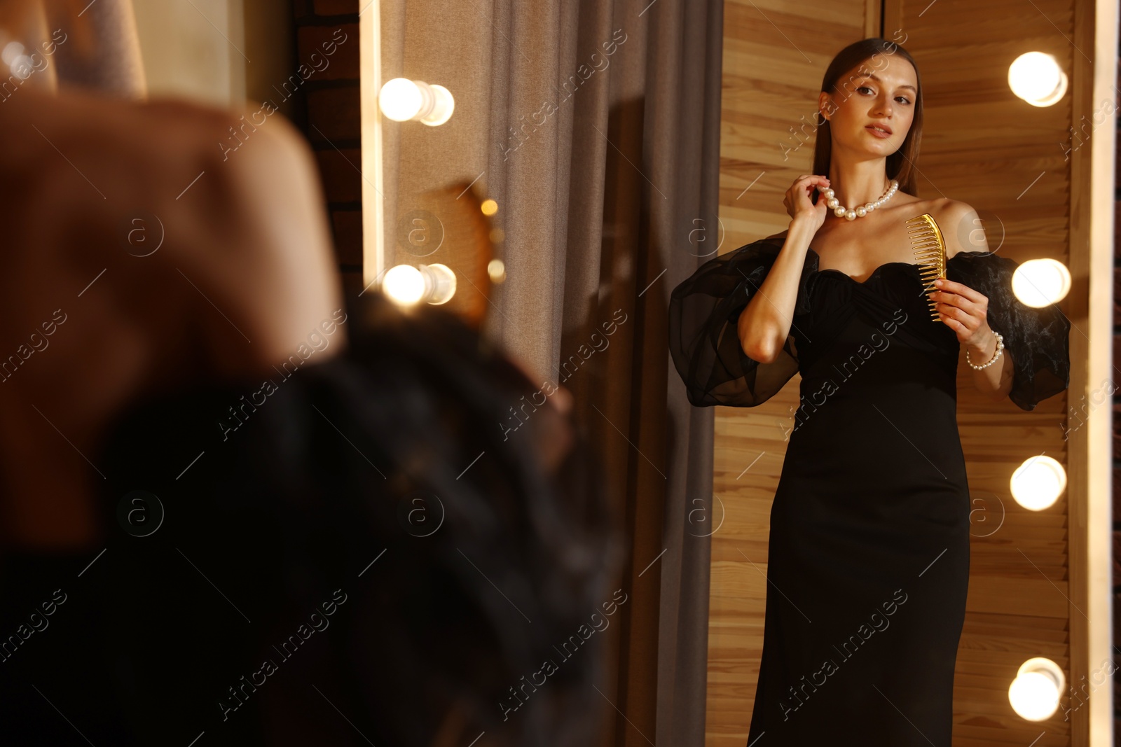 Woman with comb getting ready near mirror indoors Photo of Woman with comb getting ready near mirror indoors