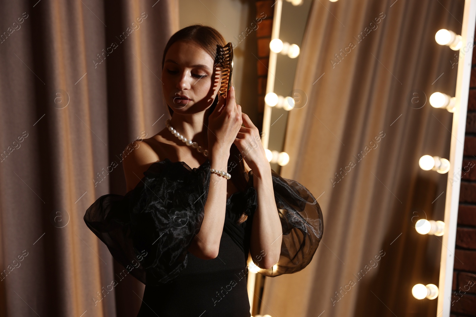 Beautiful woman brushing her hair while getting ready near mirror indoors Photo of Beautiful woman brushing her hair while getting ready near mirror indoors