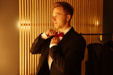 Photo of Handsome man with bow tie getting ready indoors